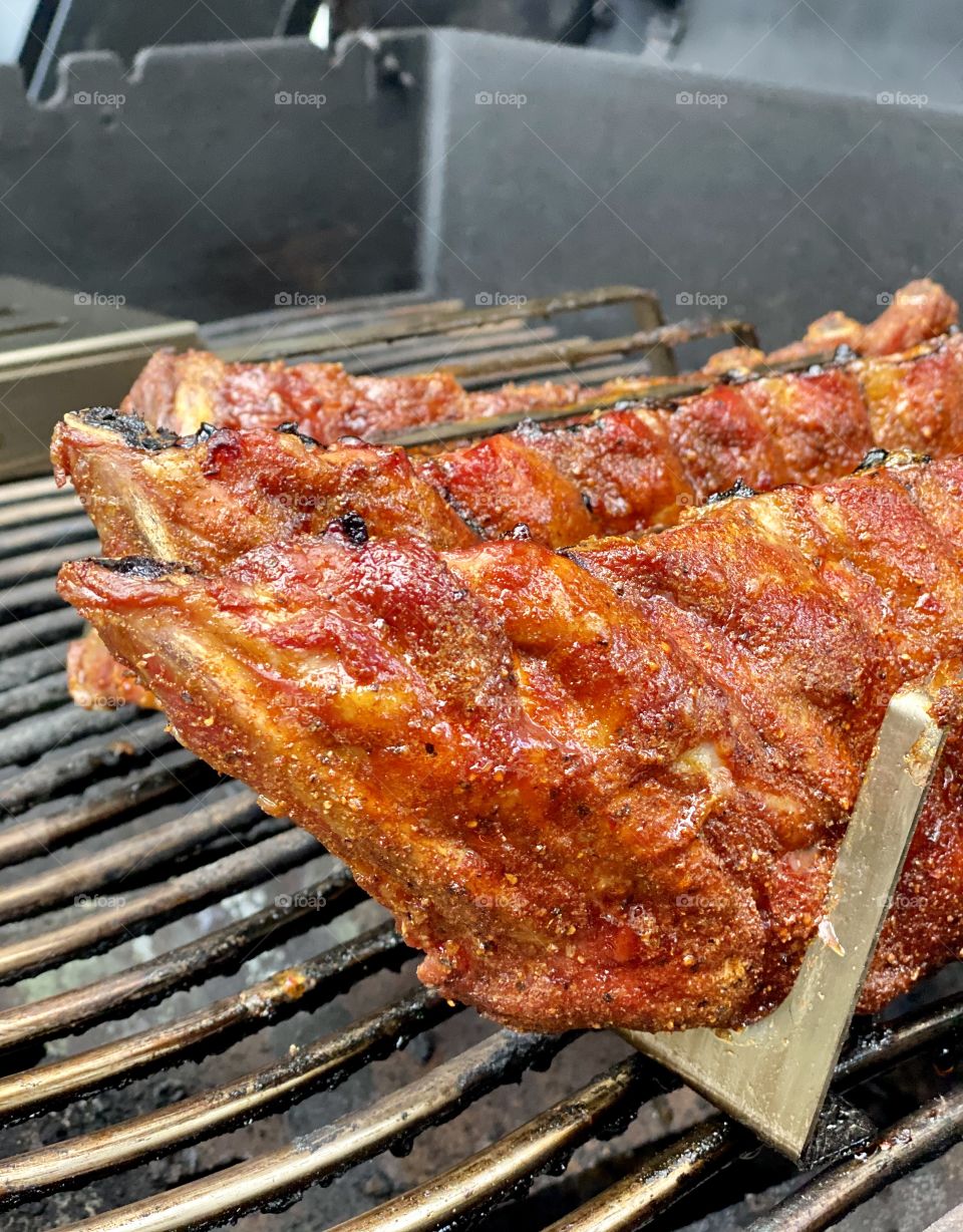 Spareribs in a rack with homemade rub on a barbecue 