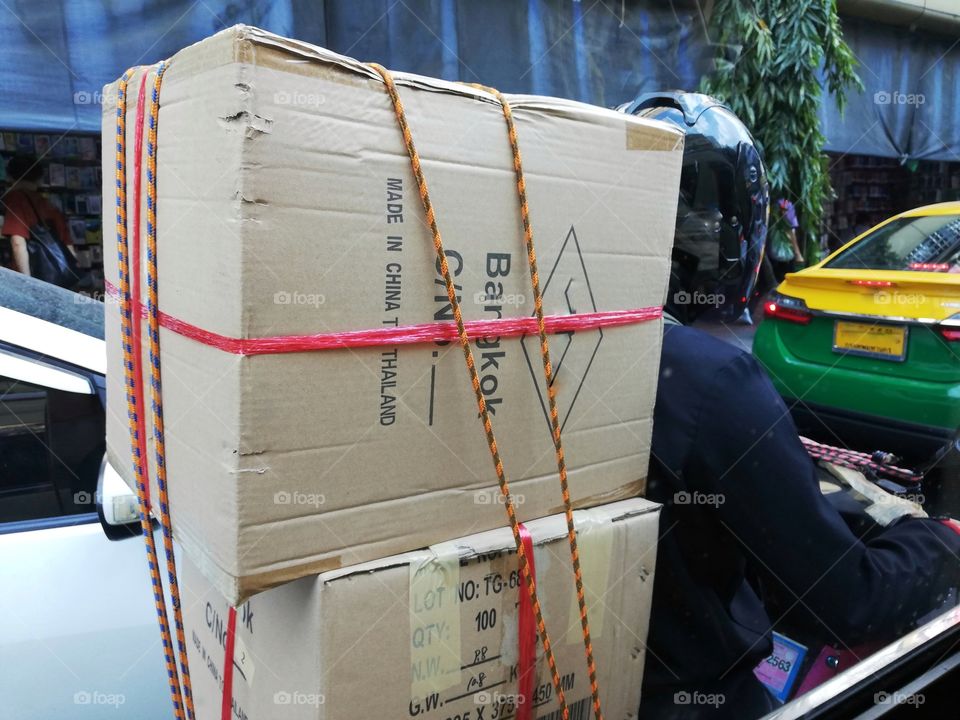 Delivery boy on motorbike delivering parcels through the streets of Bangkok