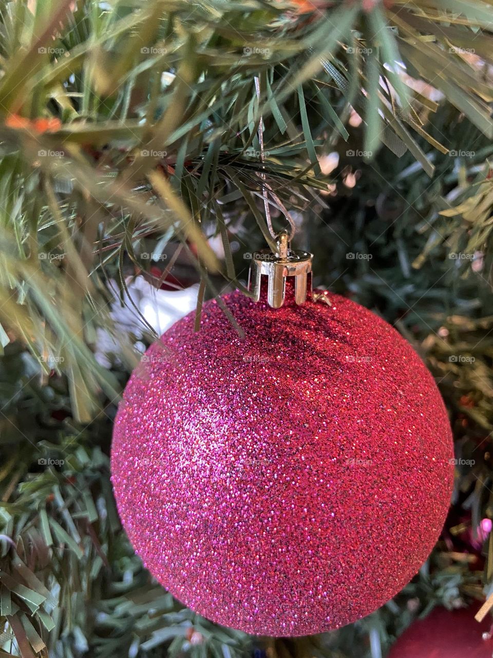 A sparkly magenta Christmas ball ornament hanging from a Christmas tree at a Panera Bread restaurant in Brick, NJ.