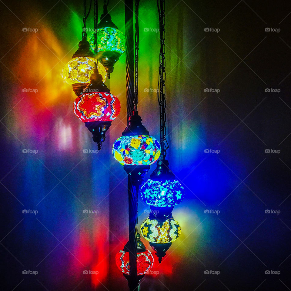 A set of moorish style lamps, colourfully illuminate a dark corner 