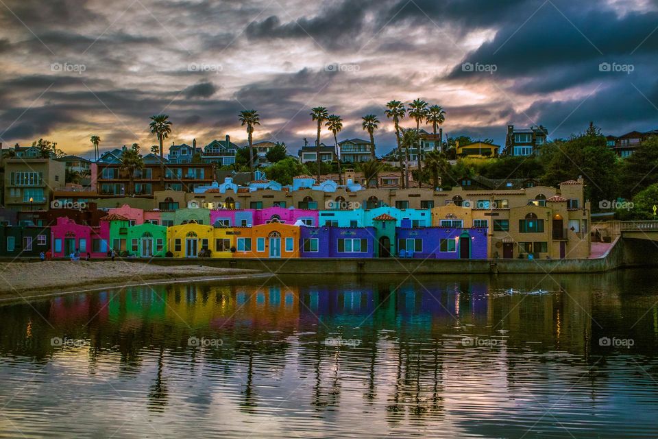 Just as dusk is beginning to set in Capitola by the Sea in California, with the sandy beach and the reflection of the colorful Venetian on the Soquel River, this landmark of the coastal town vibrant with color and the clouds in the dramatic sky.