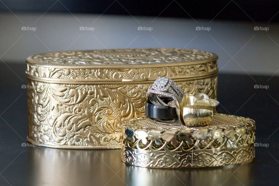 Bride and grooms wedding rings perched on an engraved decorative gold box