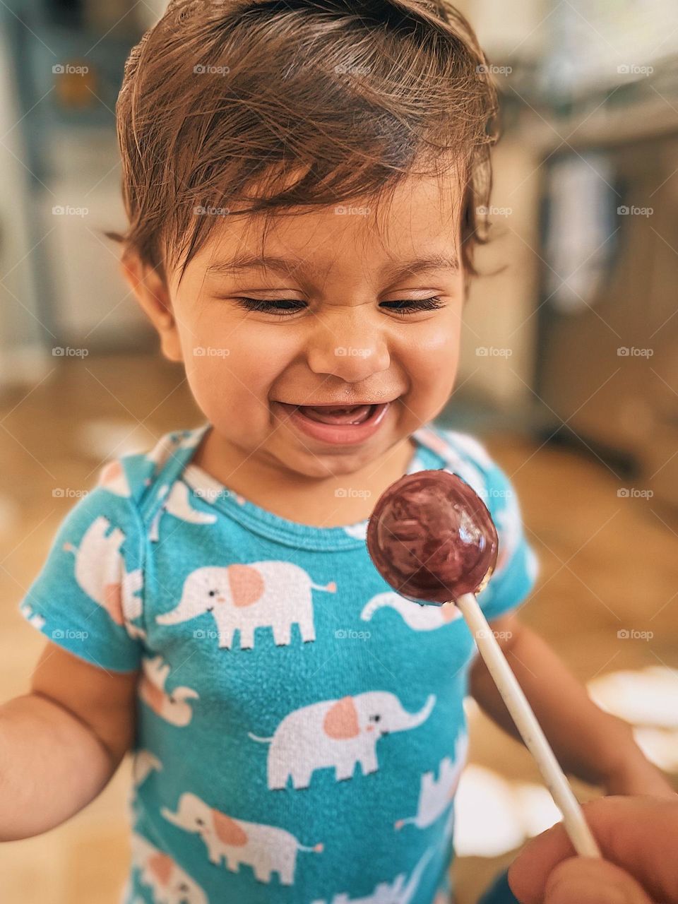 Happy toddler eats lollipop, toddler looks at lollipop with happiness, happiness in food, excited about sucker, expression of happiness, facial expressions of happiness, toddler is happy, expressing emotions