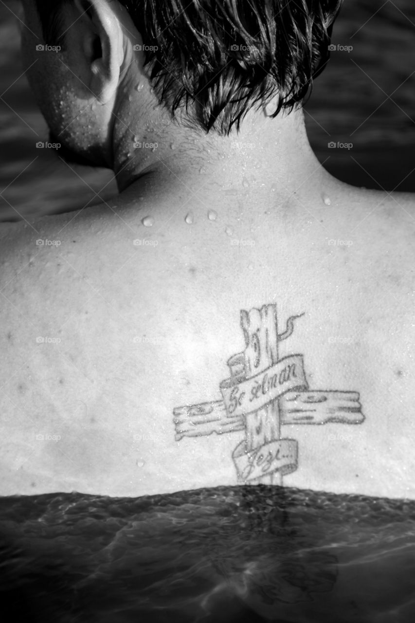 man with a tattoo in the river water black and white tattoo of a cross