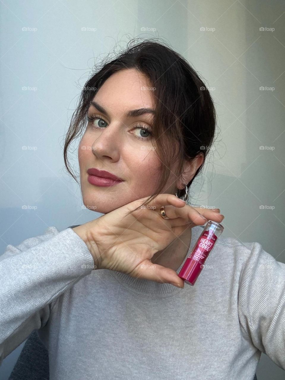 Woman’s portrait with product, girl holding a lipstick in her hands 