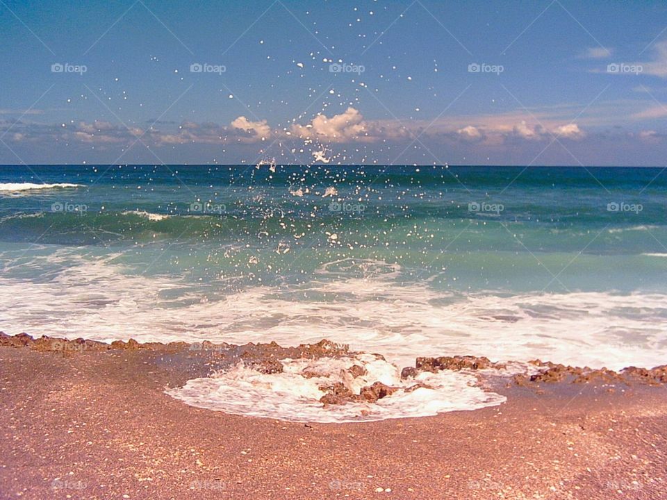 Surf splashing up through coquina coastline at Blowing Rocks Preserve Jupiter, Florida