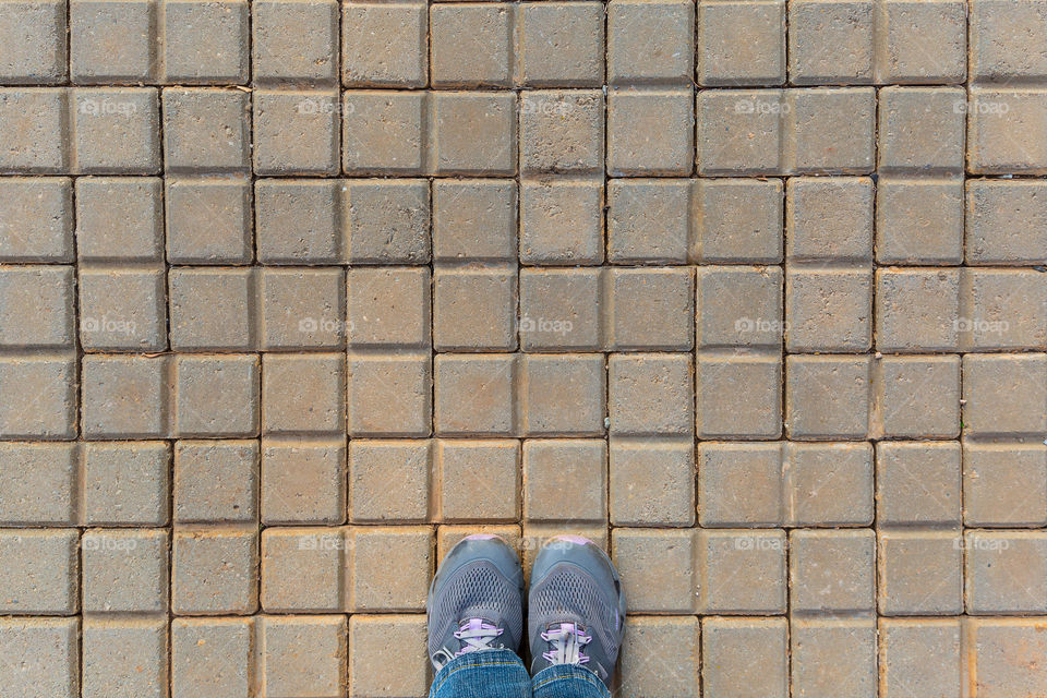 Shapes squares and rectangles on block cobble stones with grey shoes as the focus point in this symmetrical image