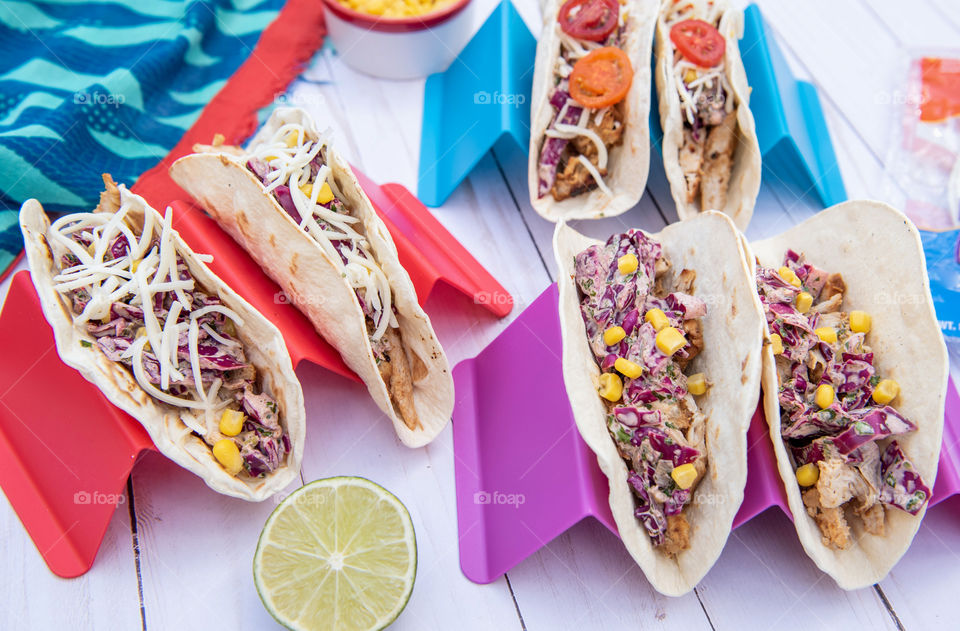 Close-up of prepared tacos in colorful taco stands on a table
