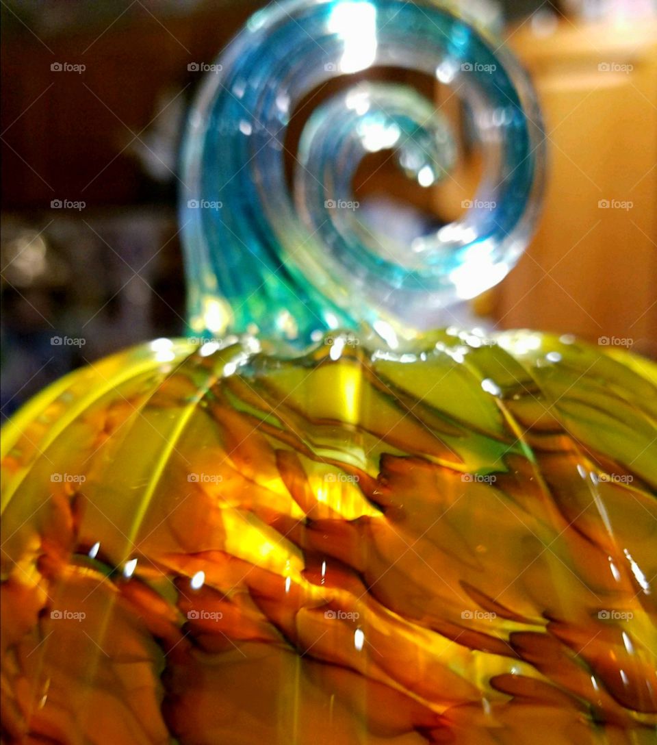 Handblown glass orange & green pumpkin with colored striations. It's got a spiral shaped blue stem, sparkling in the light.