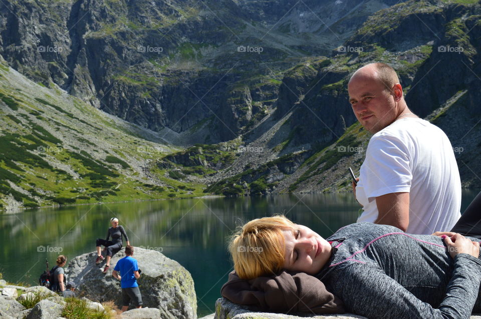 Family resting on rock near lake