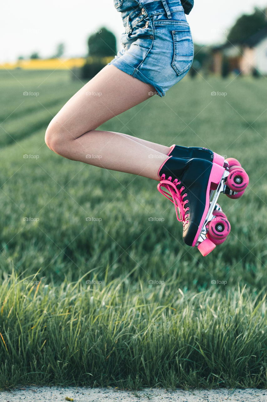 Teenage girl having fun rollerskating, jumping, spending time on summer day. Teenage smiling happy girls having fun walking outdoors, hanging, spending time together on summer day. Real people, authentic situations