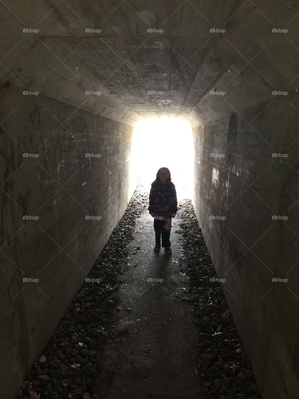 Tunnel under the tracks. Picture of my daughter standing at the end of a tunnel under some railroad tracks. 