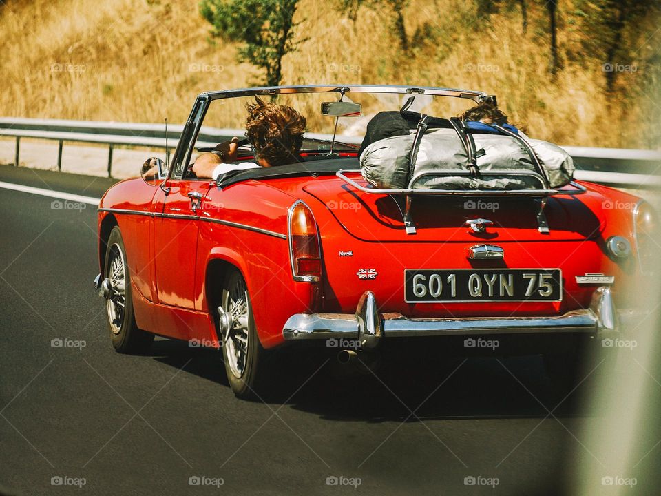 Beautiful Vintage red car, with two young people, travelling to Spain for summer holiday.