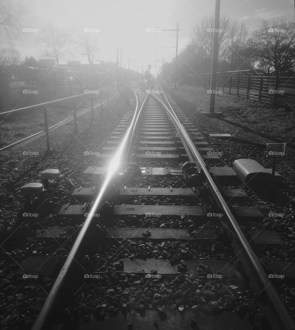Railway switch at a station in a town in the Netherlands. The sun is reflected in the rails.