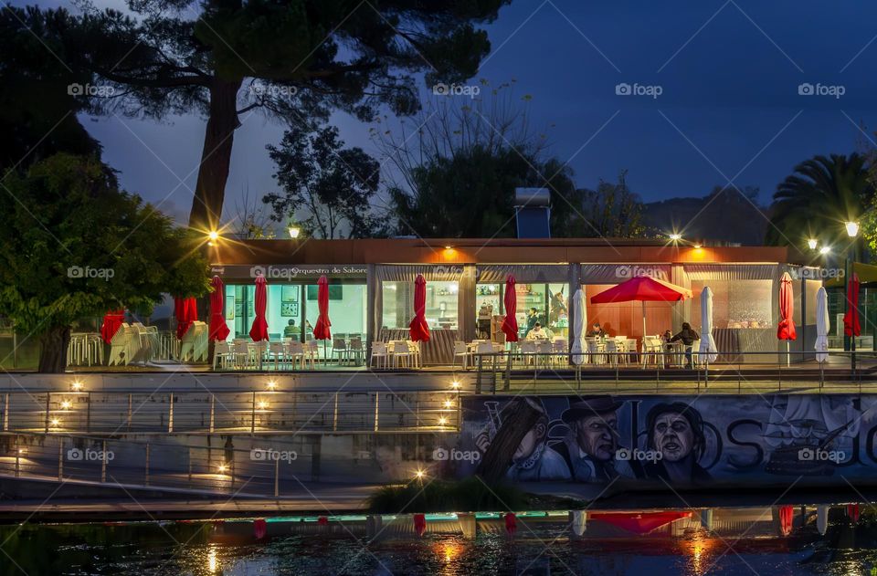 The few customers of the day seen through the windows of a riverside cafe