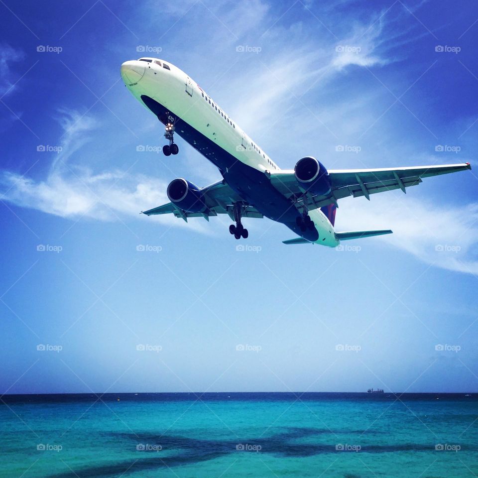 Airplane flying over ocean, flying to spring break, Maho Beach in St. Maarten, famous beaches of the world, plane in the sky 