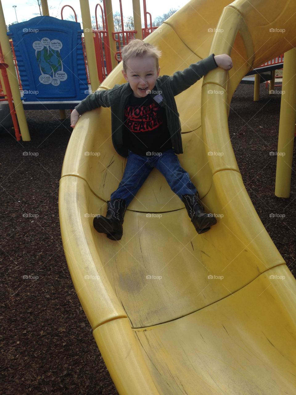 Cute boy enjoying slide in park