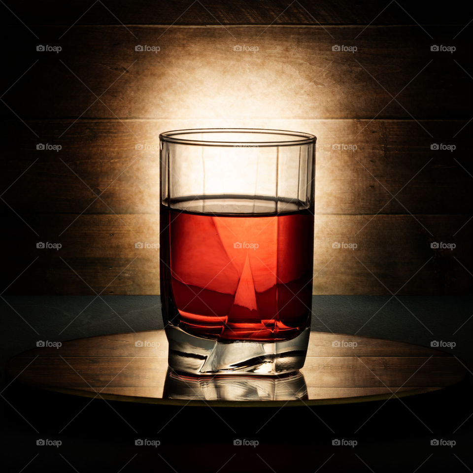 red drink in a glass. mirror table. wooden background