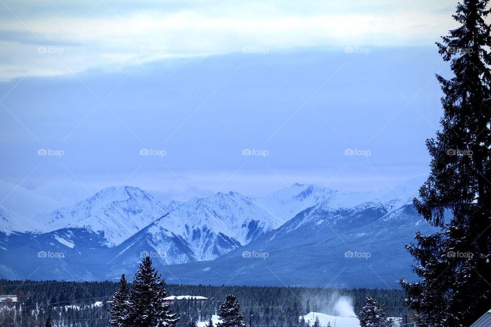 A small valley town surrounded by snow topped mountains.