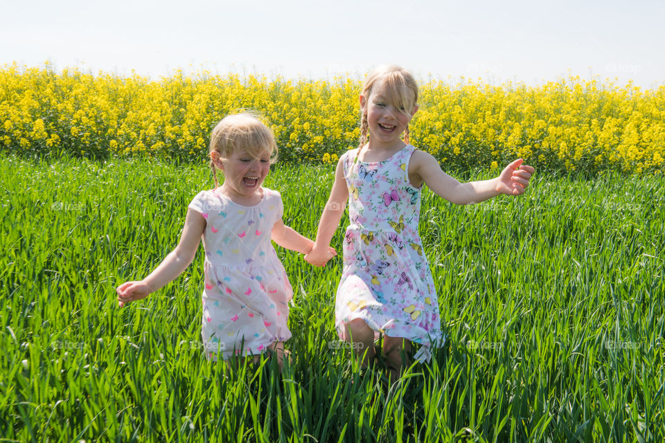 Two young sisters a running in a Raps field outside Malmö Sweden.