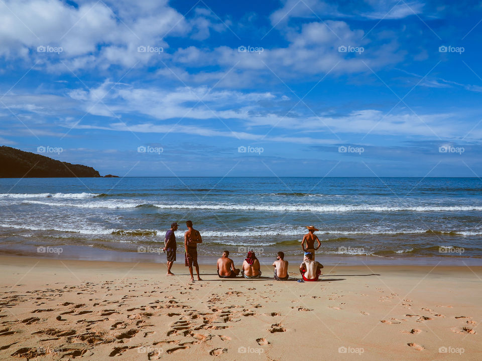 Sunrise at the Atlantic Ocean, beautiful shot of 7 men at the beach. Blue Ocean and blue sky at Praia do Sono, Brasil.
