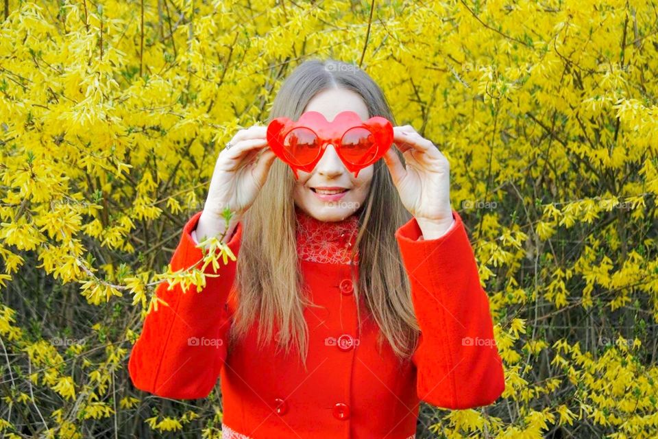 Girl in red with heart sunglasses and yellow flowers in the background