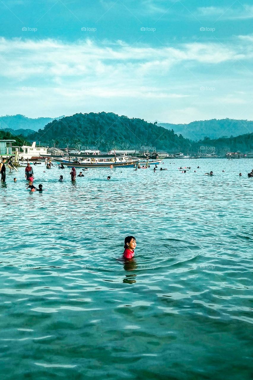 Bandar Lampung, Lampung, Indonesia - October 11, 2023: Visitors are swimming at the beach in Mutun Beach, Lampung, Indonesia