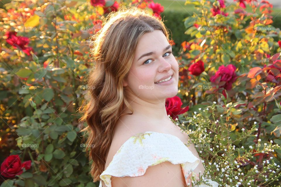 Girl sitting in field of roses on beautiful day in October 3rd early Fall