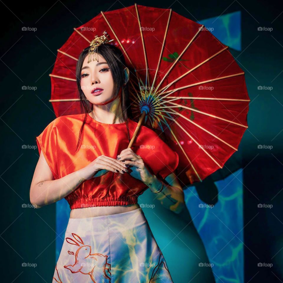 Portrait of a young woman in traditional dress complete with umbrella