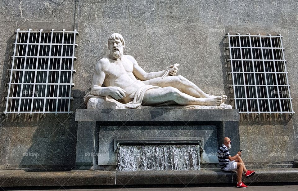 Man sitting on a fountain with statue in the center of Turin