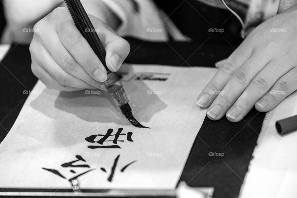 Calligraphy writing in progress, hands in frame