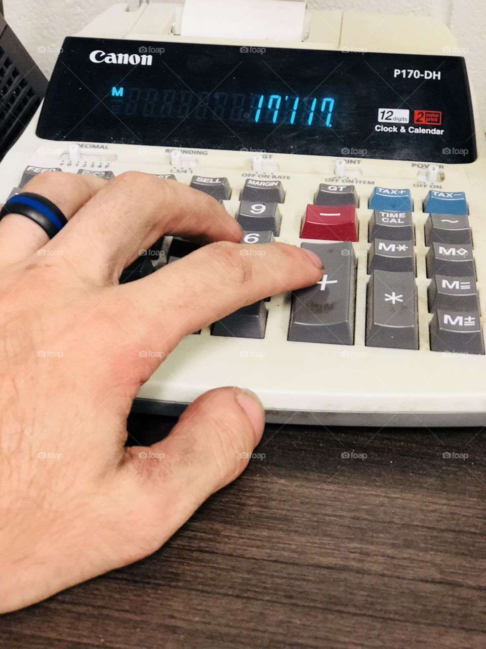 Dirty workers hand making calculations on a old school calculator 
