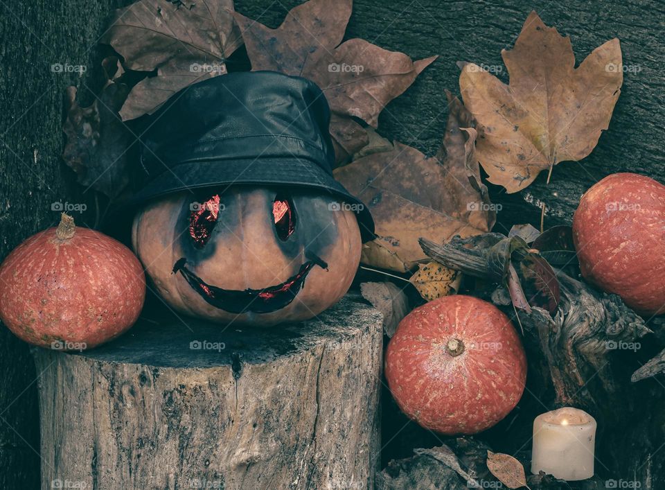 Creepy carved pumpkin with red glowing eyes in an autumnal setting