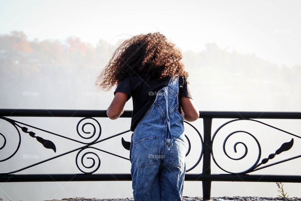 Teenage girl in a denim overall with a gorgeous curly hair