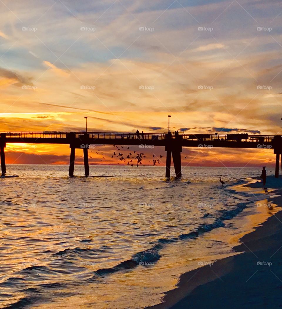 Day and night Foap Missions - A spectacular sunset at the Okaloosa fishing pier. Birds fly around the pier in hopes of finding a few bait fish. The sun shimmers across the top of the ocean as the waves break to the shore