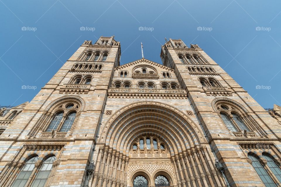 A wide view of the front of the Natural History Museum in London on a bright day