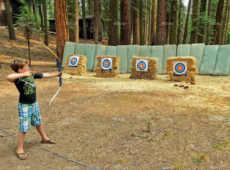 Archery. Boy Shooting Arrows At An Archery Range
