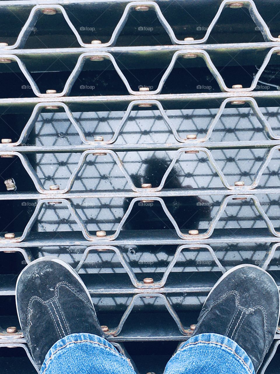 My shadow silhouette on the water through the storm drain and my black shoes
