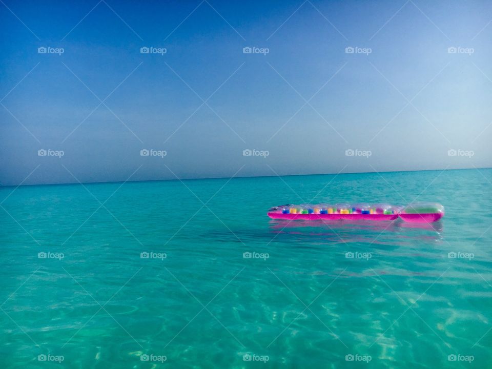 Pink sun lounger floating in turquoise waters 