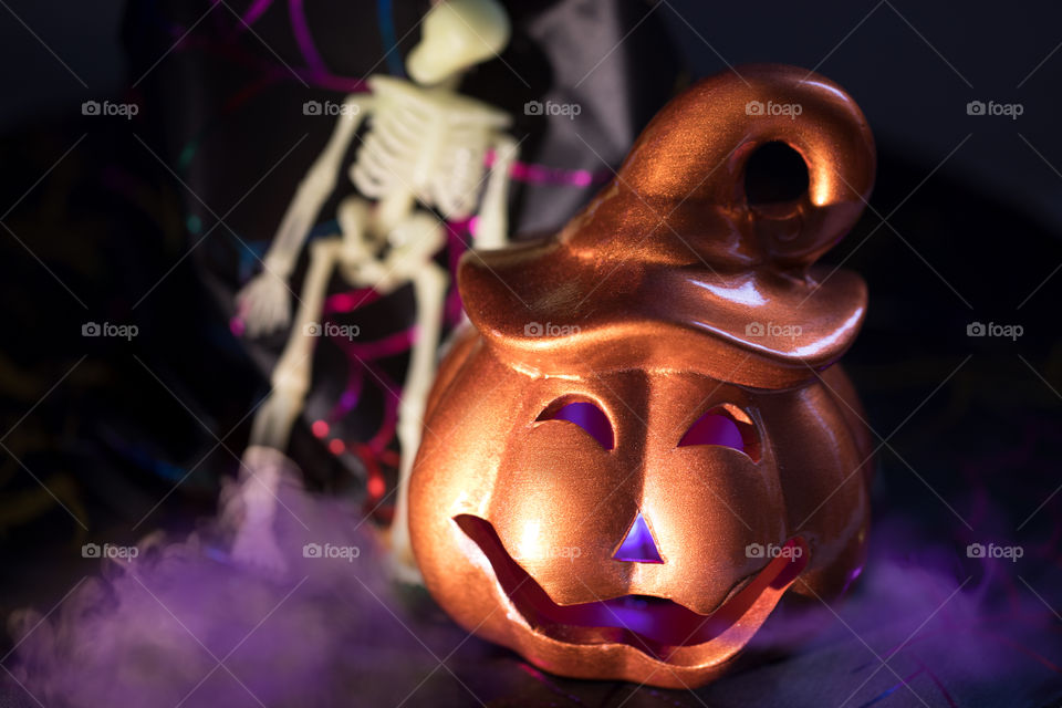 Halloween scary jack-o-lantern  burning pumpkin with sceleton and violet smoke