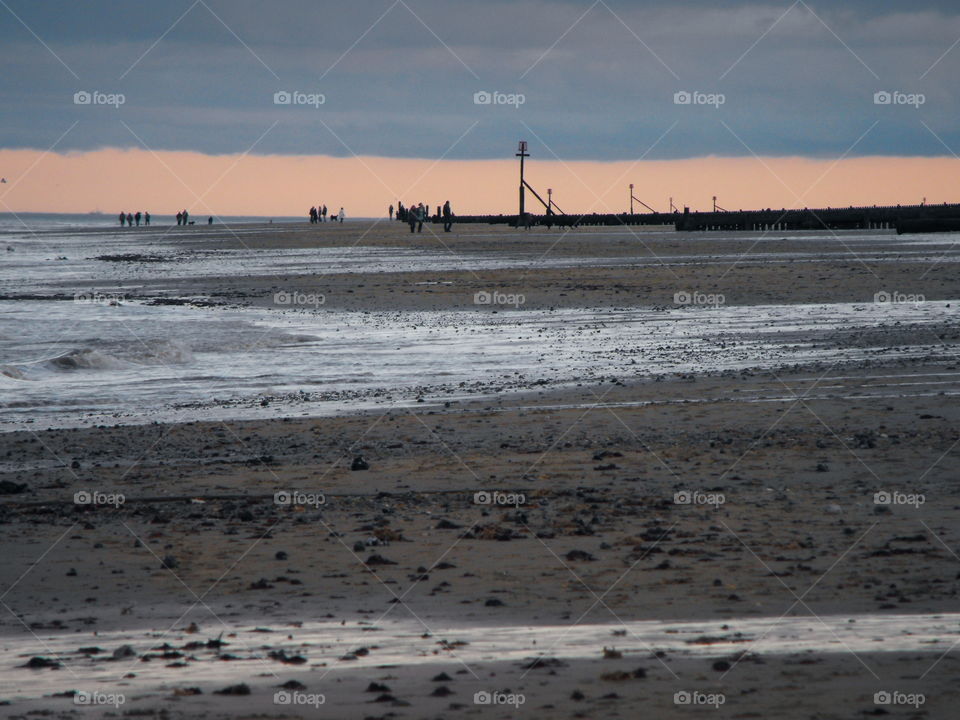 People walking along the beach at low tide