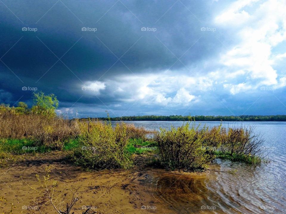 Sky with clouds and river bank at sunset