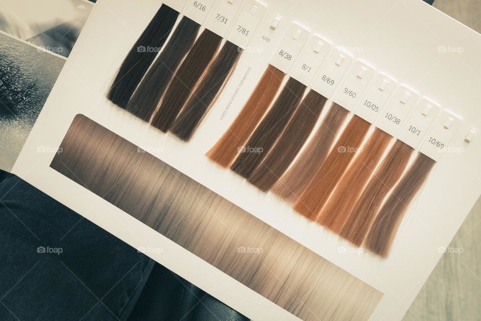 Long artificial palette of hair strands on a white cardboard book with numbers, close-up top view. Concept of a hairdressing salon, colorist services, beauty salon and hair coloring.