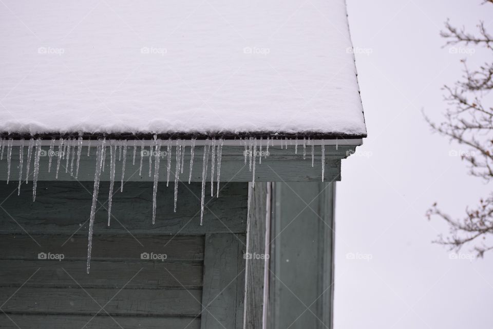 Icicles hanging from the roof of the house in late Autumn.