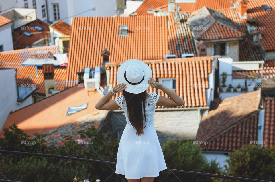 Beautiful woman traveler in white dress wondering of the old town of Piran, Slovenia. Summertime activities.