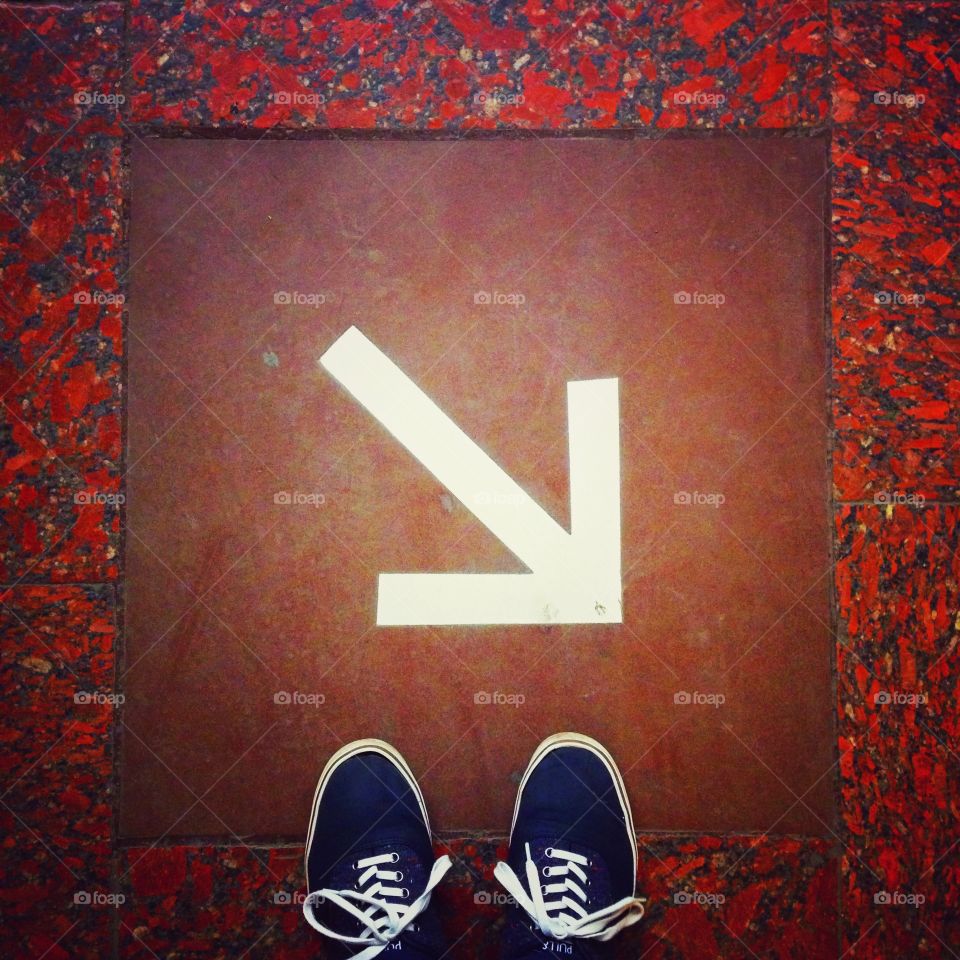 Blue shoes in front of the white arrow on the floor