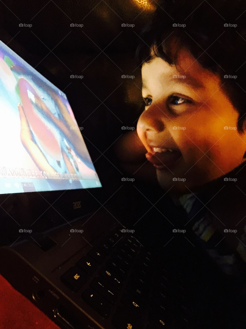 Delighted digital illumination. My son is delighted as he watches cartoon on laptop 