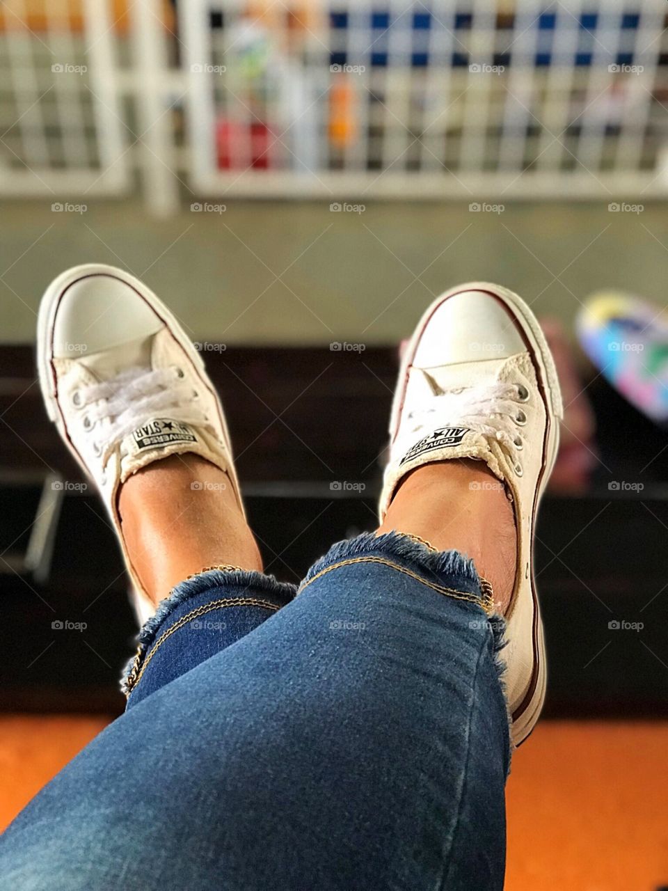 Legs stretched out wearing white sneakers all-star converse. 