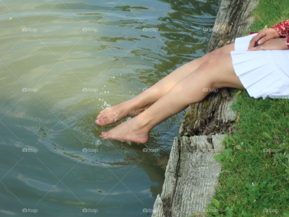 woman sitting with her legs dipped in lake water in summer