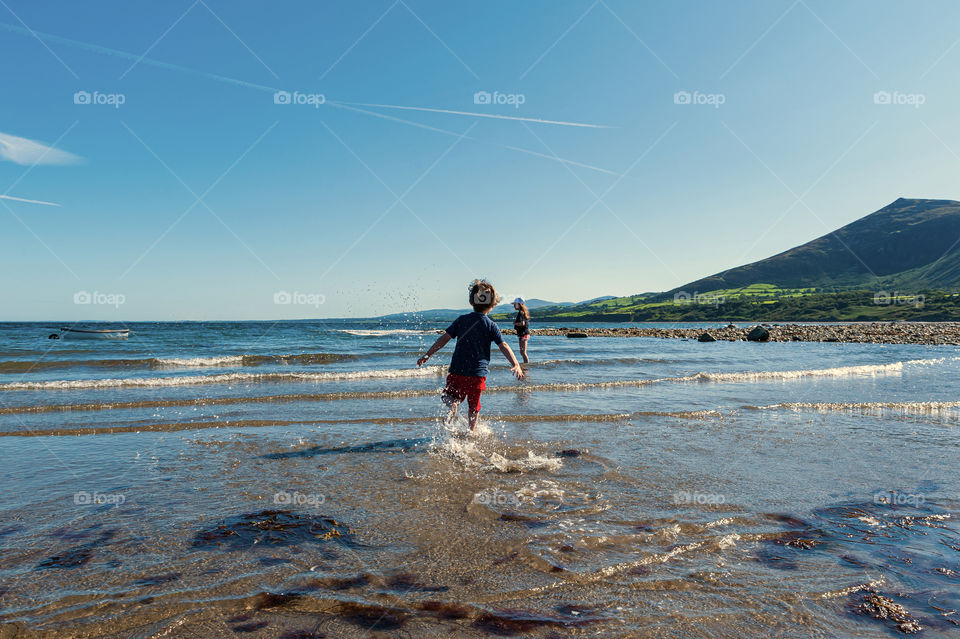 Small boy enjoys low tide in sea bay.